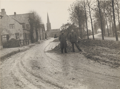 0362-G120 2 heren poseren voor de werkzaamheden met op de achtergrond de toren van de N.H.-kerk