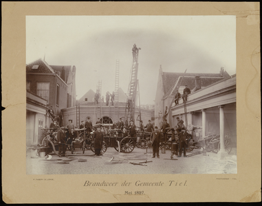 186 Een groepsfoto van de brandweer van Tiel met uitrusting waaronder brandweerladders, gemaakt op het Korenbeursplein ...