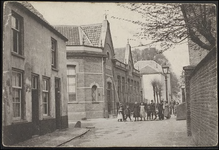 B 7.9 Op de hoek van de R.K. Lagereschool aan de Kromme Elleboog, met lantaarnpaal op de hoek en kinderen op straat. ...
