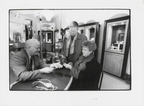 M 7256 Foto van Juwelier Langelaar die in zijn winkel een ketting laat zien aan een man en vrouw