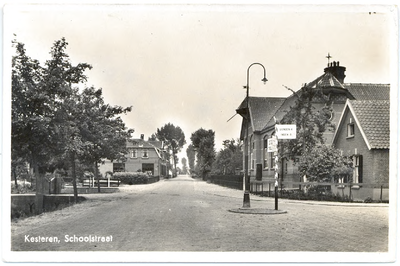 1134 Een prentbriefkaart van de Schoolstraat (Hoofdstraat) in Kesteren, met een ANWB-wegwijzer en op de achtergrond de ...