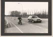 0360-512 De Hoofdstraat in Kesteren richting Rhenen en de afrit N233. Een scooter en een auto
