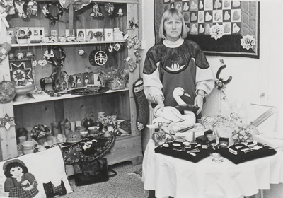 0362-127 Winkeleigenaresse Maria Boone tussen haar verkoopwaar in haar zojuist geopende winkel