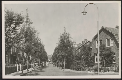 B 4.3 Straat met eengezinswoningen, bomen, lantarenpaal op de hoek en vrouwen op de straat.