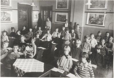 M 10209 Schoolklas; leerlingen met onderwijzeressen, schoolplaten aan de muur