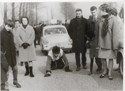 10908 Weddenschap kruipen de kruiperd; geflankeerd door toeschouwers kruipt een jonge man voor een Trabant 600