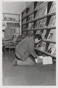 M 11497 De bibliotheek aan de Sint Agnietenstraat 28 in Tiel voor de verbouwing van 1987. Een man zit op zijn knieen ...