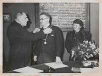 M 12095 De loco-burgemeester wethouder A.M. Ebben, hangt de nieuwe burgemeester Cambier van Nooten de ambtsketting om. ...
