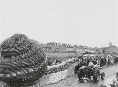 M 2824 Op de Nieuwe Tielseweg rijdt een van de corsowagens tijdens het Oogst-fruitcorso langs het publiek. Op de ...