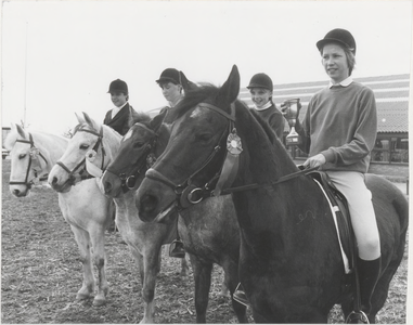 M 4255 De Roskam manege, met leerlingen en de paarden, een leerling heb een beker in haar hand waarschijnlijk hebben ze ...