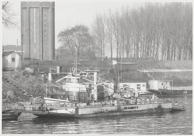 M 4810 Motorveerboot Gijsbert Stout met pont Zeldenrust II afgemeerd langs de Waaldijk. Op de achtergrond de Watertoren