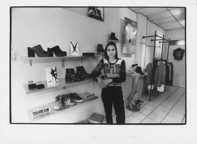 M 7216 Jonge vrouw, poserend in een schoenen- en kledingwinkel in de Kerkstraat in Tiel