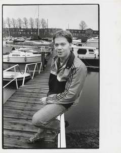 M 7289 Foto van een jongeman zittend op de aanlegsteiger van de haven bij Culemborg met op de achtergrond de Veerweg