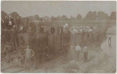 M 8943 Waarschijnlijk uiterwaarden Wamel, mannen in een treintje, aantal andere mannen poseert voor het treintje.