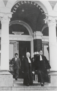 M 9108 Twee heren gekleed in toga's rechterlijke macht voor Rechtbank Tiel, daarachter nog aantal personen