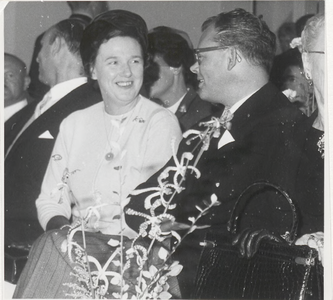 M 9156 Mevr. Stolk (links), zit naast man met wie zij in gesprek is, meerdere personen zitten achter en naast haar