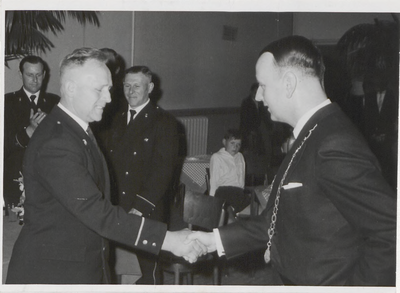 M 9209 Rechts Burgemeester Stolk, schudt handen met man in uniform, terwijl twee andere mannen toekijken