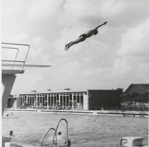 M 9219 Een zwemmer springt vanaf de hoge duikplank. Op de achtergrond het filtergebouw