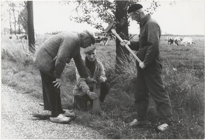 M 9424 Drie mannen in overall slaan paaltje langs berm