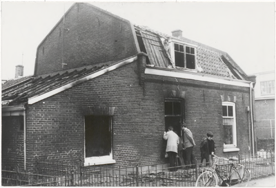 M 9475 Woning in Postlaantje na brand, enkele personen kijken naar binnen, naast hen een jongen met fiets