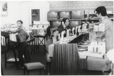 9562 Uitbreiding radio-tv-platenzaak Hendrich aan de Waterstraat, jonge klanten, waarvan twee luisteren met ...