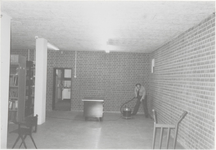 0690-2426 Dhr. W. Veerman bezig met stofzuigen voor het plaatsen van de rolkasten in de kluis van het archief op ...