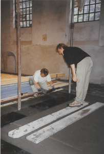 0690-3958 Tegelzetter bij het aanbrengen van de vloertegels in de kerk A. Winkel rechts kijkt toe.