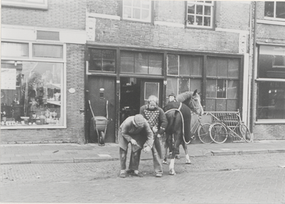 6 Smederij familie Heij in de Zandstraat 69 (nu nummer 23), met Marius Heij in actie; links de bijbehorende winkel ...