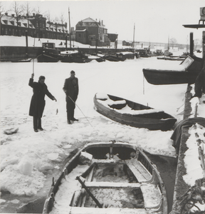 106 Twee vissers op de bevroren haven. Op de achtergrond de huizen aan de Veerweg en de spoorbrug.