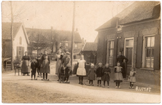 1087 Een prentbriefkaart met dorpsbewoners in de omgeven van de R.M. van Gellicumstraat in Rumpt. Bij de voordeur staat ...