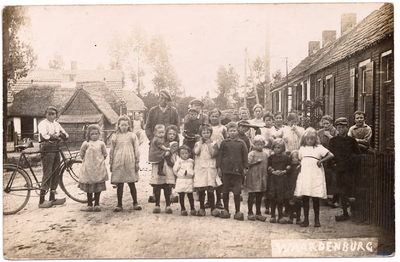 1097 Een prentbriefkaart van een straat in Waardenburg met op de voorgrond poserende kinderen en volwassenen