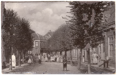 1124 Een prentbriefkaart van de Zandstraat in Culemborg met poserende straatbewoners en passanten