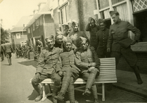 1122 Mobilisatie Kesteren en omgeving : groep militairen zittend op en staand bij een bank voor een rij woonhuizen