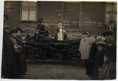 4-668 Een koets met daarin staand Sinterklaas voor het gemeentehuis en eromheen een aantal toeschouwers. Vlnr: Anna ...