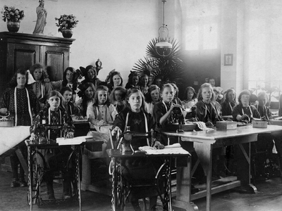 4-712 Schoolfoto: een aantal leerlingen in de banken of achter de naaimachine uit de naaiklas van zuster Marie. ...