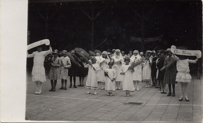 4-756 Een aantal vrouwen en meisjes gedeeltelijk in bruidskleding met een palmtak in hun handen en wat vaandels bij ...