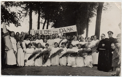 4-757 Een aantal meisjes in bruidskleding met een palmtak in hun handen voor een spandoek met als tekst hulde en dank. ...