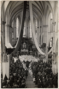 4-759 Een versierde kerk vol mensen en een aantal meisjes als bruidjes in de midden zijn 3 paters te onderscheiden.