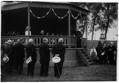 4-905 De muziektent met daarin enkele mensen, wat toeschouwers en een paar leden van de fanfare bij het muziekfeest ter ...