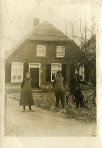 21-302 Drie personen waarvan een met een fiets buiten voor een boerderij. Te herkennen: N.W. de Waal (Vos).