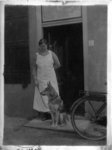 21-311 Vroedvrouw F. Rooker met hond buiten op de stoep voor haar huis.