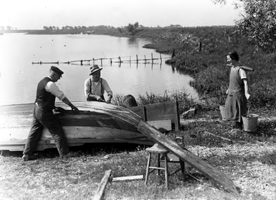 18-17001 Waterdraagster en twee mannen werkend aan een boot