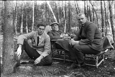 22-9562 Drie onbekende mannen in een bos, waarvan één in een gevlochten ligstoel