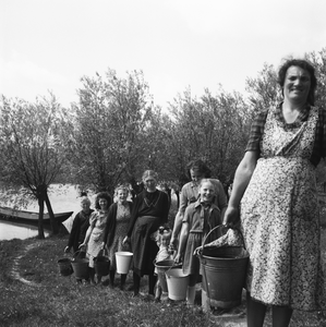 5000034_05 Bewoners aan de dijk (Slijkwellsedijk) halen water in de Afgedamde Maas. Geheel achteraan Trui van Kuijk