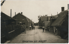 2-10047 Straatgezicht met links op de voorgrond een hooiberg en rechts een auto (M22984) en op de achtergrond een kar ...